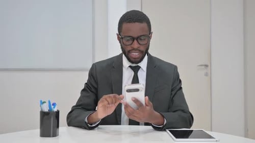 Excited Young Adult Using Smartphone in Office Setting