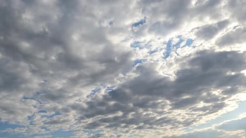 Grey clouds flow slowly by the skies. Rainy cloudscape forming in the atmosphere but then blue sky