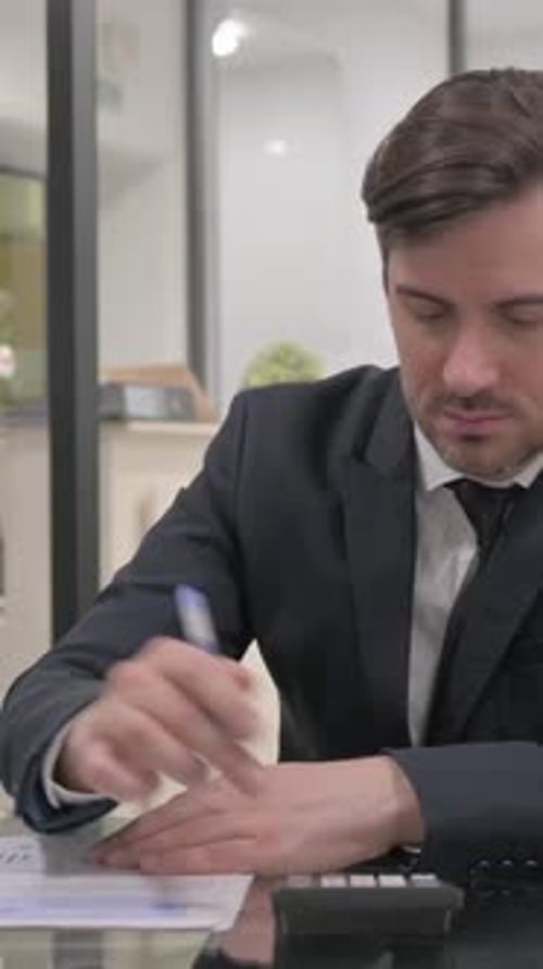 Professional Man Calculates Finances at Office Desk