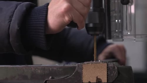 close up shot of man operating drilling machine drilling multiple holes with a golden drill in meta