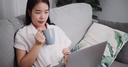 Woman Working on Laptop with Coffee at Home