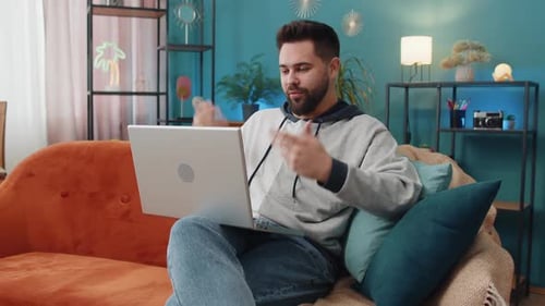 Smiling Man Video Calling on Laptop at Home