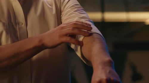 Man Rolling Up Sleeves of White Button-Down Shirt