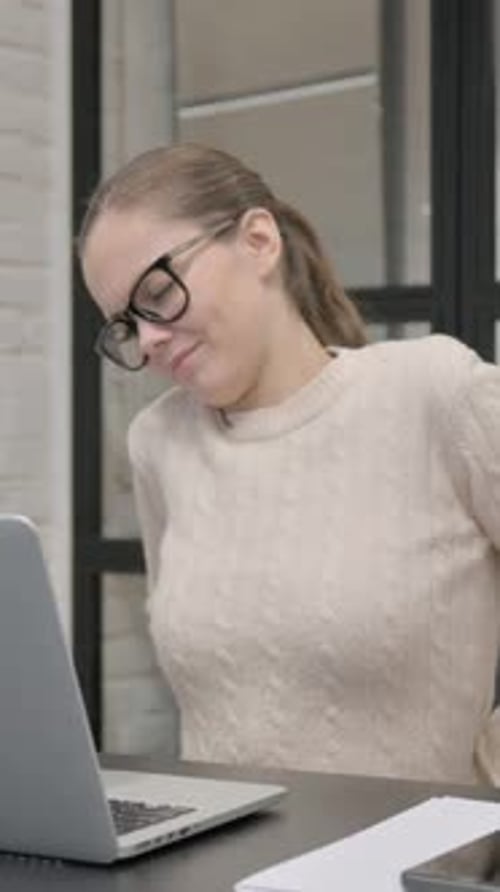Woman stretching to relieve tension while using laptop
