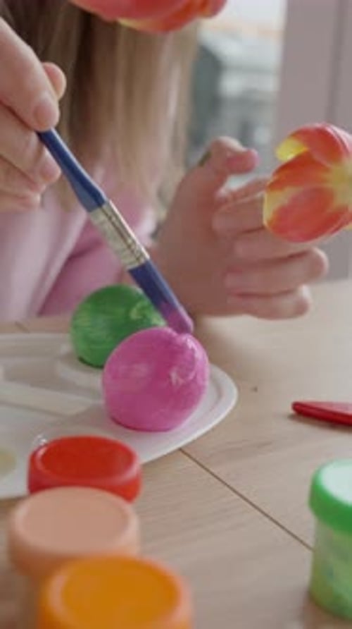 Woman painting Easter eggs at home for spring holiday