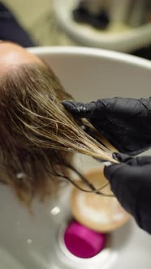 Hairdresser Washing the Hair of a Woman in Salon