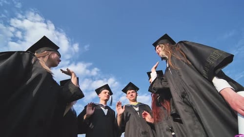 Graduates in Black School Uniforms Join Hands The Concept of Team and Strong Friendship