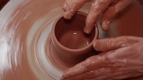 Façonner une tasse sur un tour de poterie en rotation.