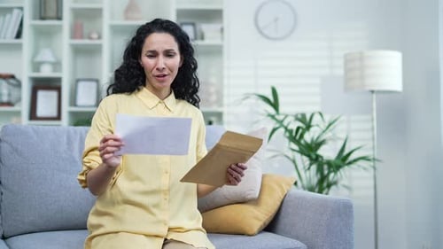 Excited Woman Reading Letter on Sofa