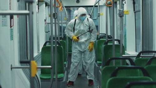 Men in protective suits disinfecting bus interior