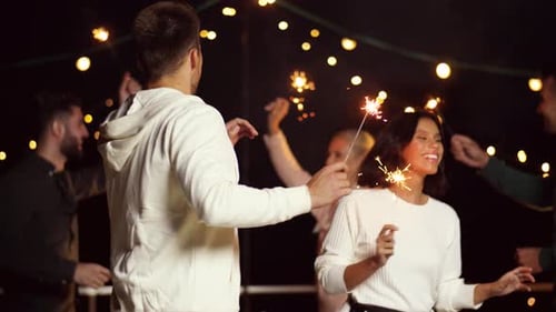 Leisure, Celebration and People Concept - Happy Friends with Sparklers Dancing At