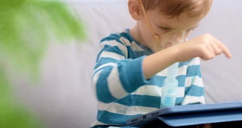 Boy Using Nebulizer While Playing on Tablet