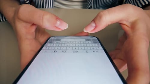 Woman Typing on Smartphone at Table Close-Up