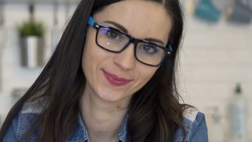 Smiling Woman with Glasses Resting Chin on Hand