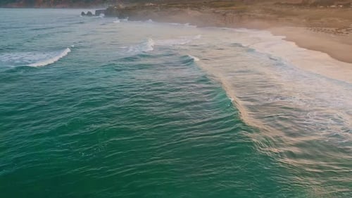 Aerial View of Waves Crashing on Beach at Sunset