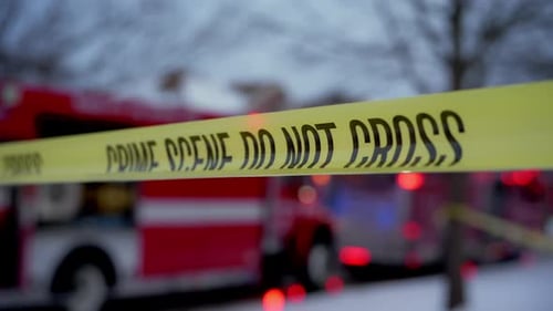 A Bright Yellow Crime Scene Do Not Cross Tape Stretched Across the Street at the Residential Area