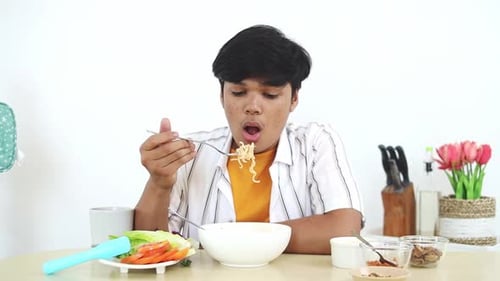 Young Adult Enjoying Bowl of Noodles at Table