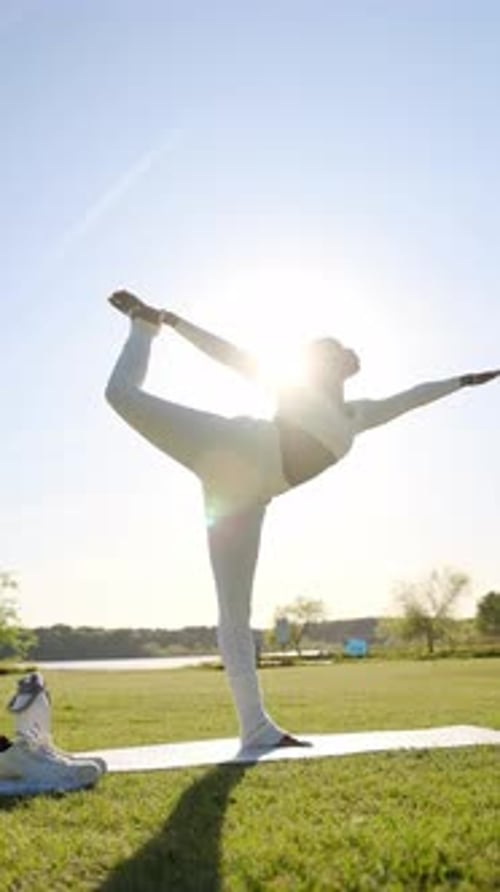 Femme noire flexible effectuant une pose de yoga Natarajasana à l'extérieur