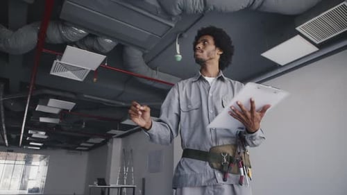 Man Inspecting Air Conditioning in Industrial Office