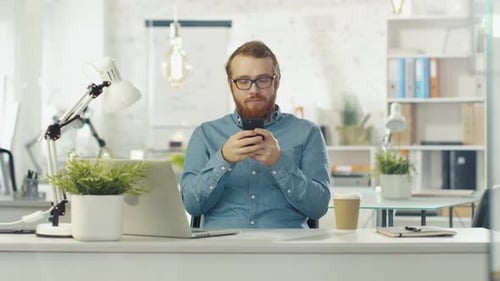 Man Uses Smartphone at Bright Modern Office Desk