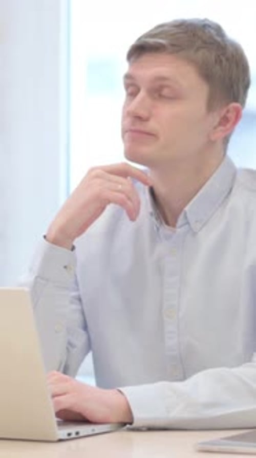 Pensive Young Man Working on Laptop at Desk