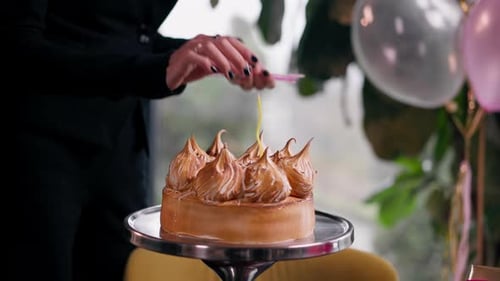 close-up of delicious appetizing cake hand puts candle during birthday celebration in restaurant