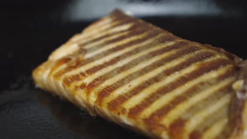 Salmon slice cooked on frying pan. Slow motion shot. Close up