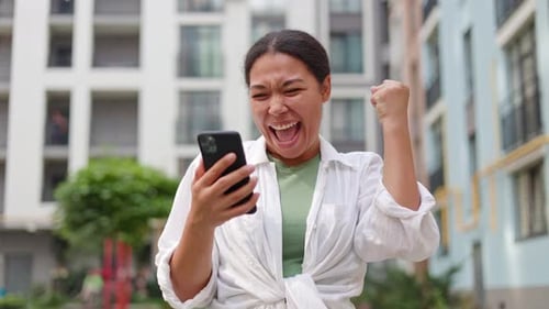 Woman Celebrates Good News on Mobile Phone