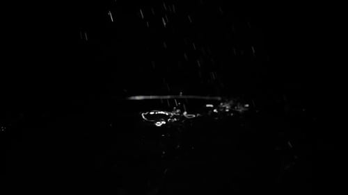 Drops of Water Breaks on the Water Surface on a Black Background