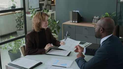 Financial Consultant Discussing Report with Female Client at Office Meeting