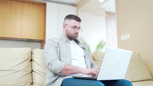 Man Using Laptop Computer Sitting on Couch
