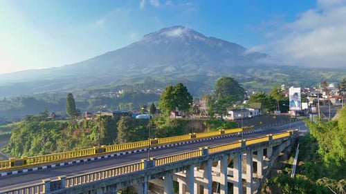 Des véhicules circulent sur le pont de Sigandul avec le mont Sumbing en arrière-plan. Aérien