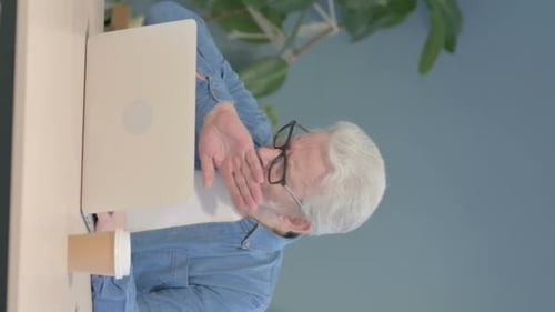 Senior Man Coughing While Working on Laptop