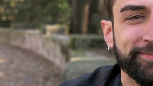 Hübscher junger Mann lächelt im Parkhalbgesicht in die Kamera
