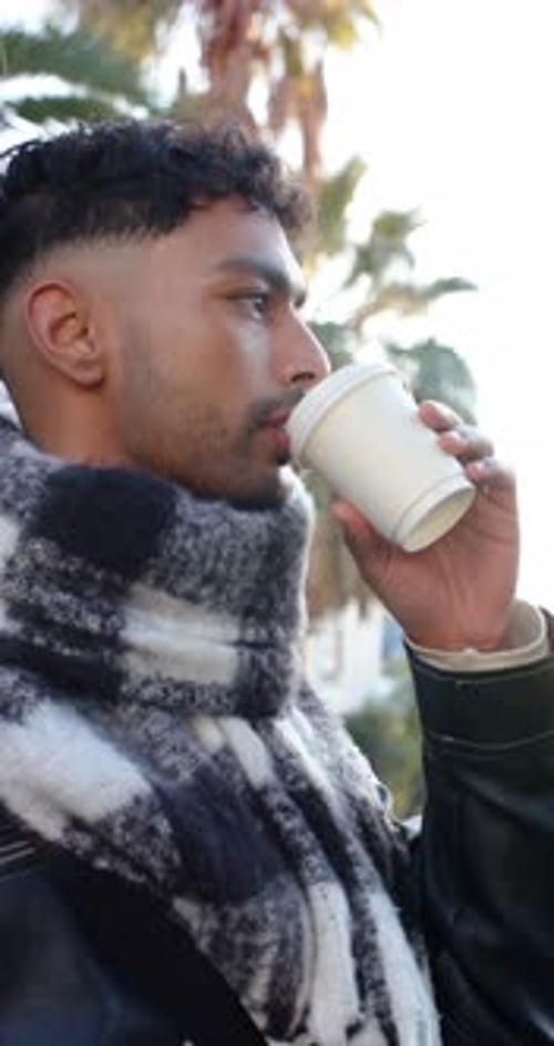 Vertical video: Male holding coffee cup sipping coffee and scanning city sidewalk to enjoy moment