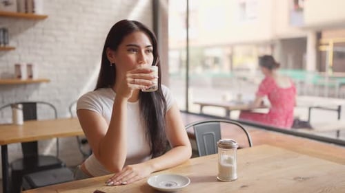 Mixed race woman drinking a cup of coffee at a table in cafe restaurant.
