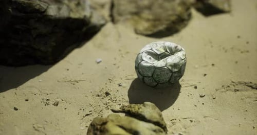 Unique Stone Resembling a Soccer Ball on Sandy Beach Surface