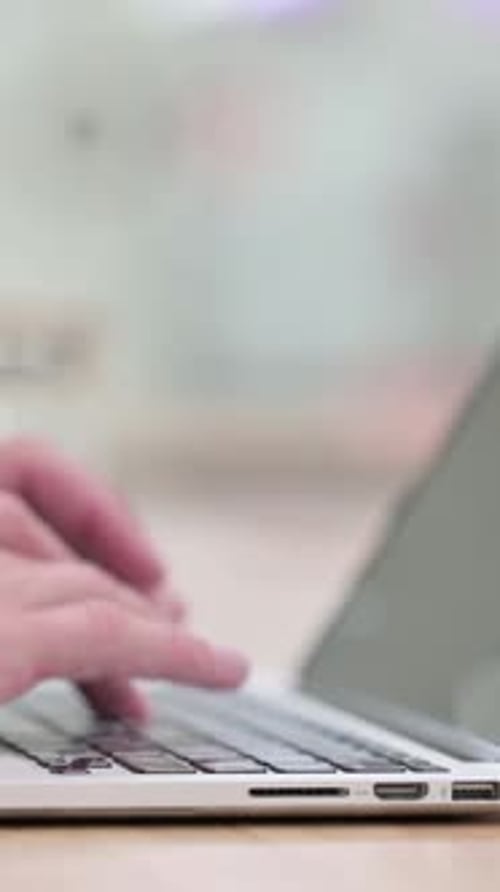 Man Typing on Laptop Keyboard in Office Setting