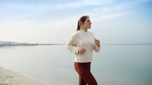 Slow motion of active and fit young woman running on the beautiful sandy beach