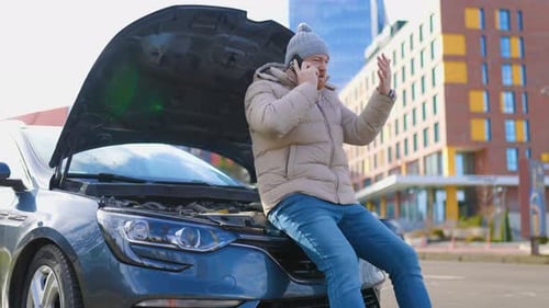 Man on Phone Next to Car on Urban Street