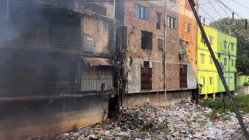 Burning fire on trash pile beside urban factory city building, pollution concept - Dhaka, Bangladesh