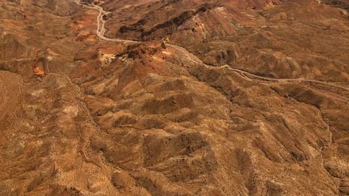 Brown dry landscape of Mojave desert. Rocky landscape with a highway in the middle. Top view.