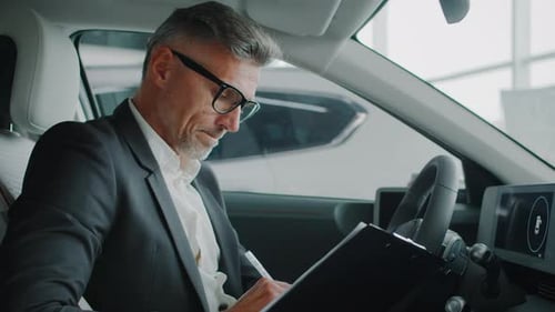 Aged Manager Defines Customer Needs Sitting in Car at Dealership