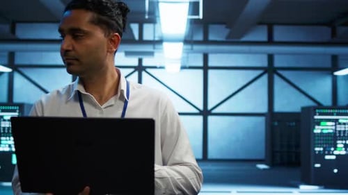 Männlicher Systemadministrator überprüft die Infrastrukturleistung mit einem Laptop im Serverraum für