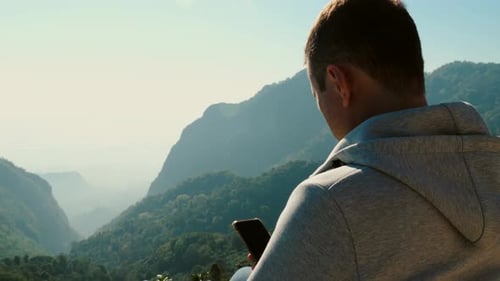 Man With Mobile Phone Overlooking Mountain Range