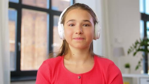 Teen Girl Waving and Talking with Headphones Indoors