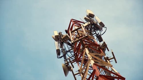 panning close up shot of communication tower with wireless antenna and blue sky at daytime