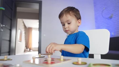 Sweet little kid playing at his desk at home. Lovely baby boy studying through the game.