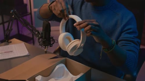 Young Adult Unboxing New Headphones in Colorful Room