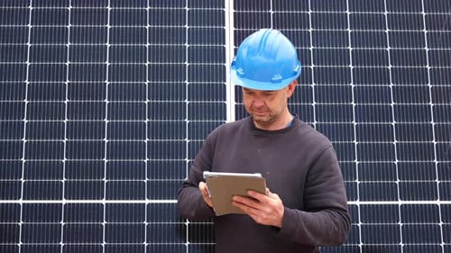 Engineer Inspecting Solar Panels with Tablet